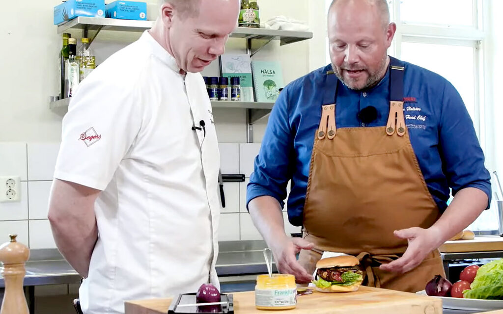 Kocken och kulinariska kreatören Johan Holster undervisar en annan kock gällande produkter från Orkla.
