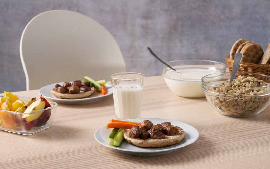FELIX Nötköttbulle med ärta serverad som frukost eller mellanmål på en macka. Havrefras och frukter syns i bakgrunden.