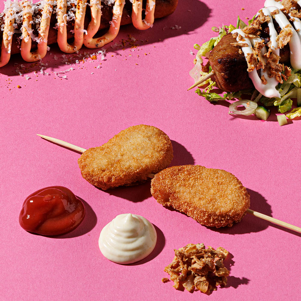 Nuggets på en pinne, som en pölse. Dipsås och rostad lök bredvid.
